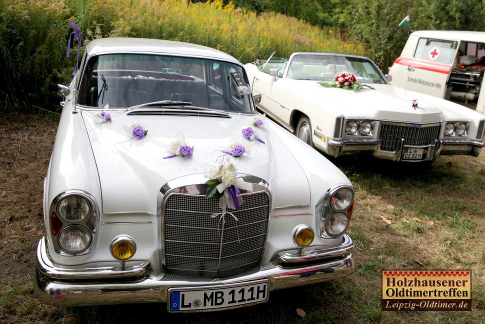 Zwei weie Oldtimer als Hochzeitsfahrzeug mit Blumen geschmckt